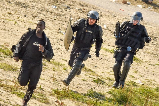 Gendarmes pursue a migrant during the dismantlement of the Jungle in 2016