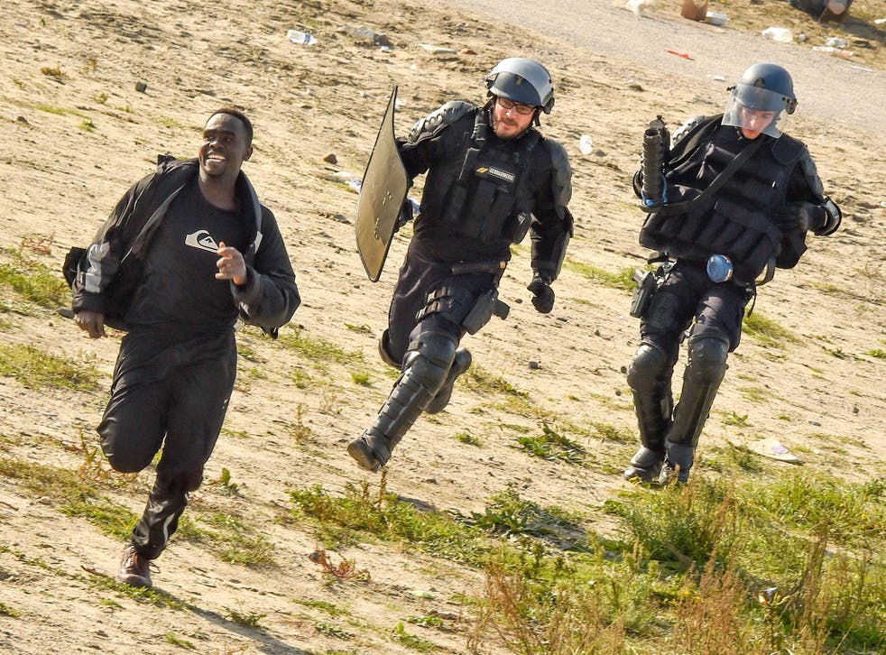 Gendarmes pursue a migrant during the dismantlement of the Jungle in 2016