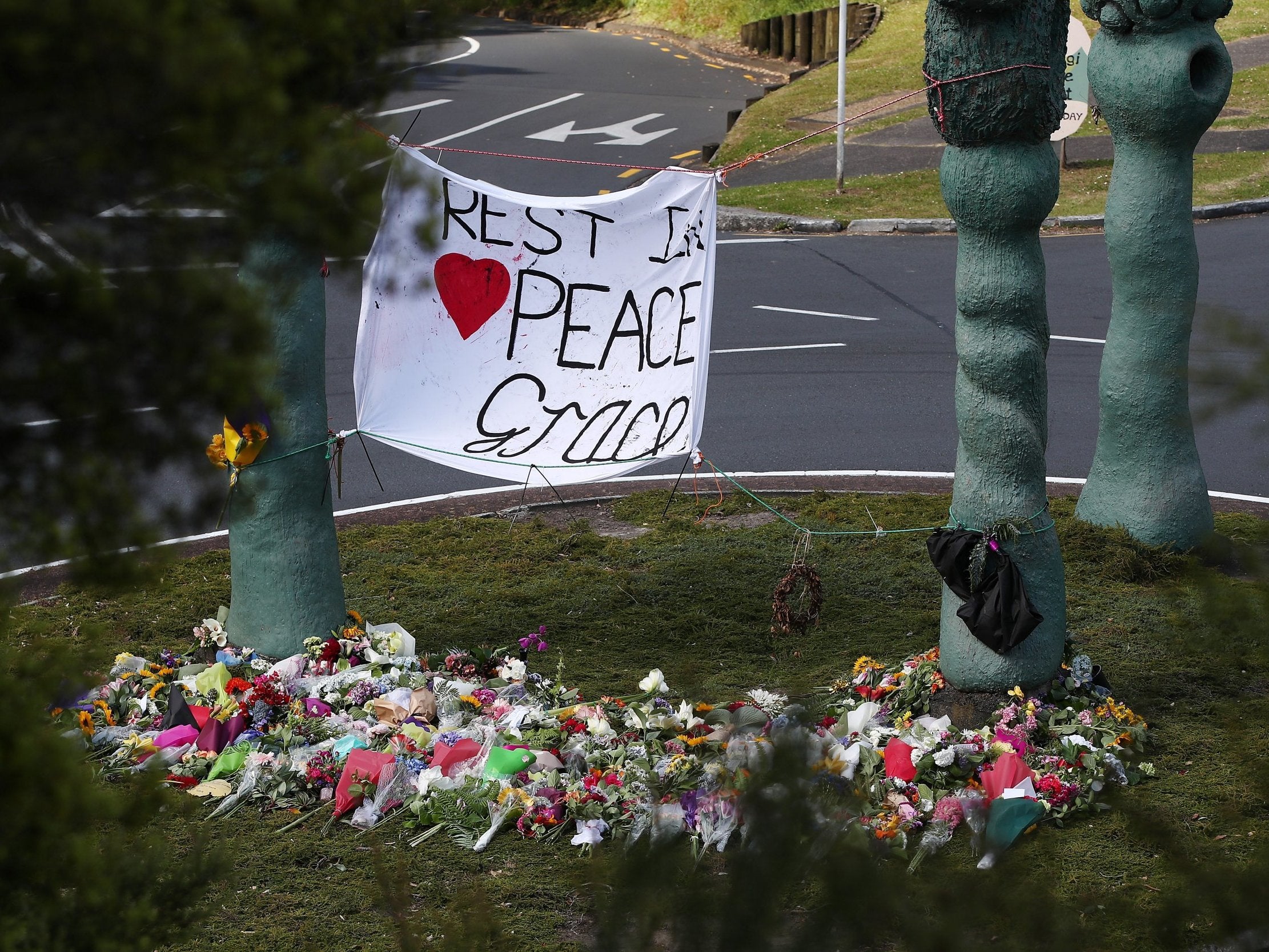 Tributes to Grace Millane are left at a roundabout in Titirangi in Auckland (Getty)