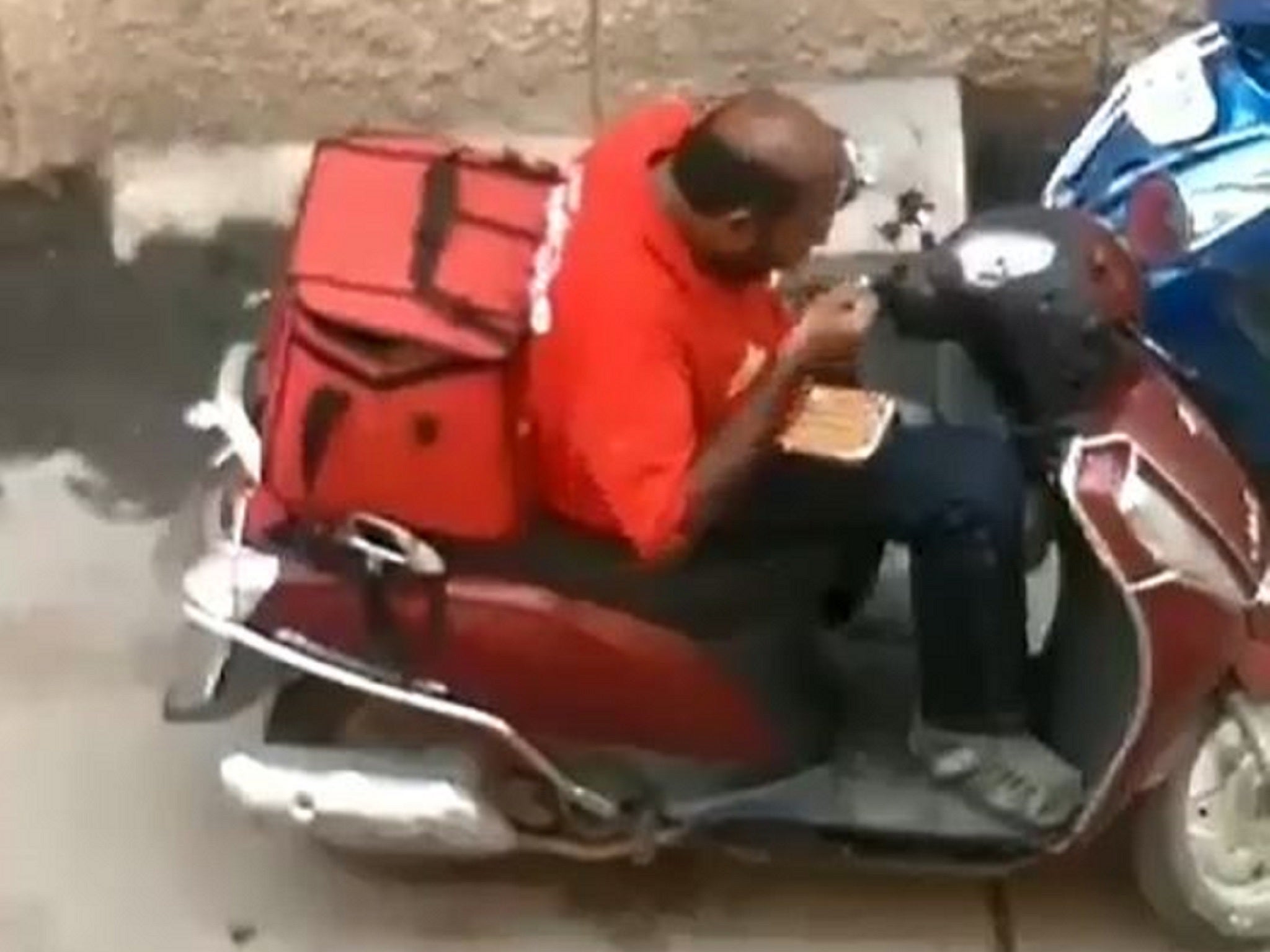 A Zomato delivery driver has been sacked after a video emerged of him sitting on a moped eating part of a customer's takeaway before resealing the food containers and putting them back in his delivery bag in Madurai, India.