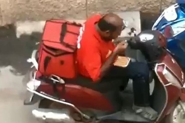 A Zomato delivery driver has been sacked after a video emerged of him sitting on a moped eating part of a customer's takeaway before resealing the food containers and putting them back in his delivery bag in Madurai, India.