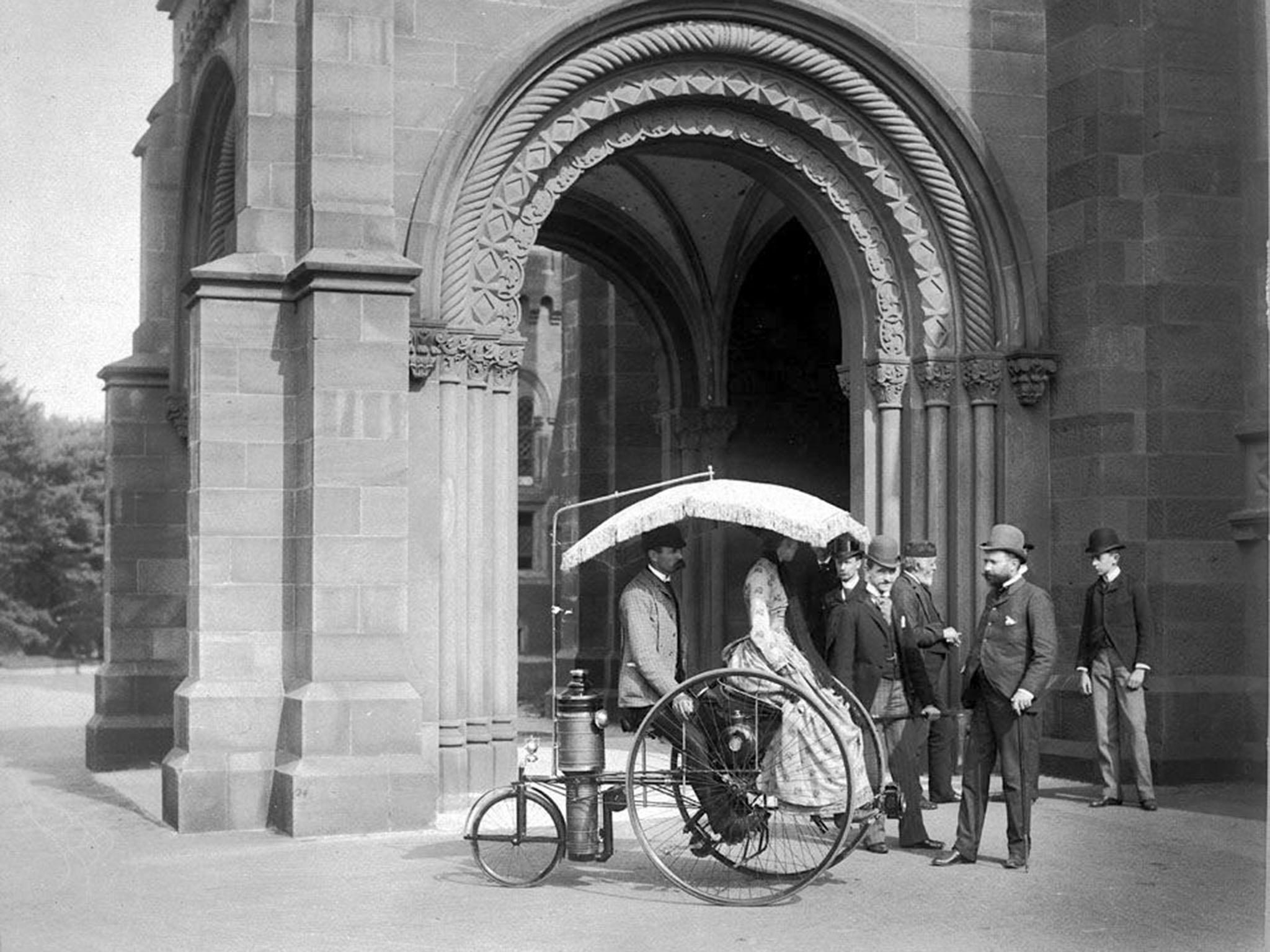 A couple ride a Copeland steam-propelled tricycle outside the castle in 1888