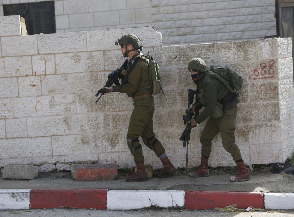 Israeli soldiers conduct a search for suspects o in the shooting attack near Ofra