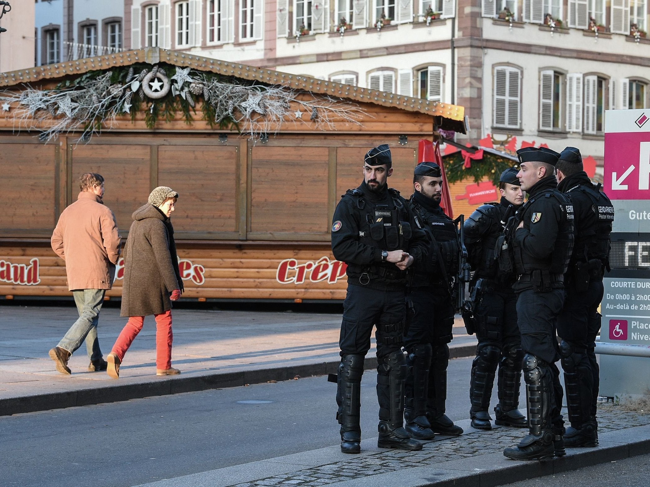 People walk past French Gendarmes who are standing guard in central Strasbourg two days after the deadly shooting