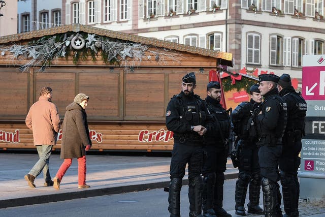 People walk past French Gendarmes who are standing guard in central Strasbourg two days after the deadly shooting