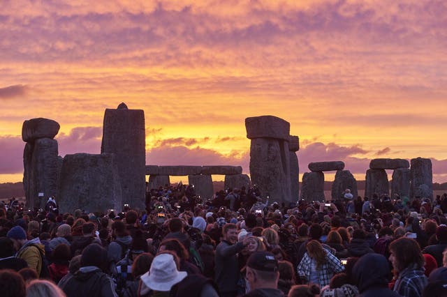 Revelers watch the sunrise as they celebrate the pagan festival of Summer Solstice at Stonehenge in Wiltshire, southern England on 21 June 2018