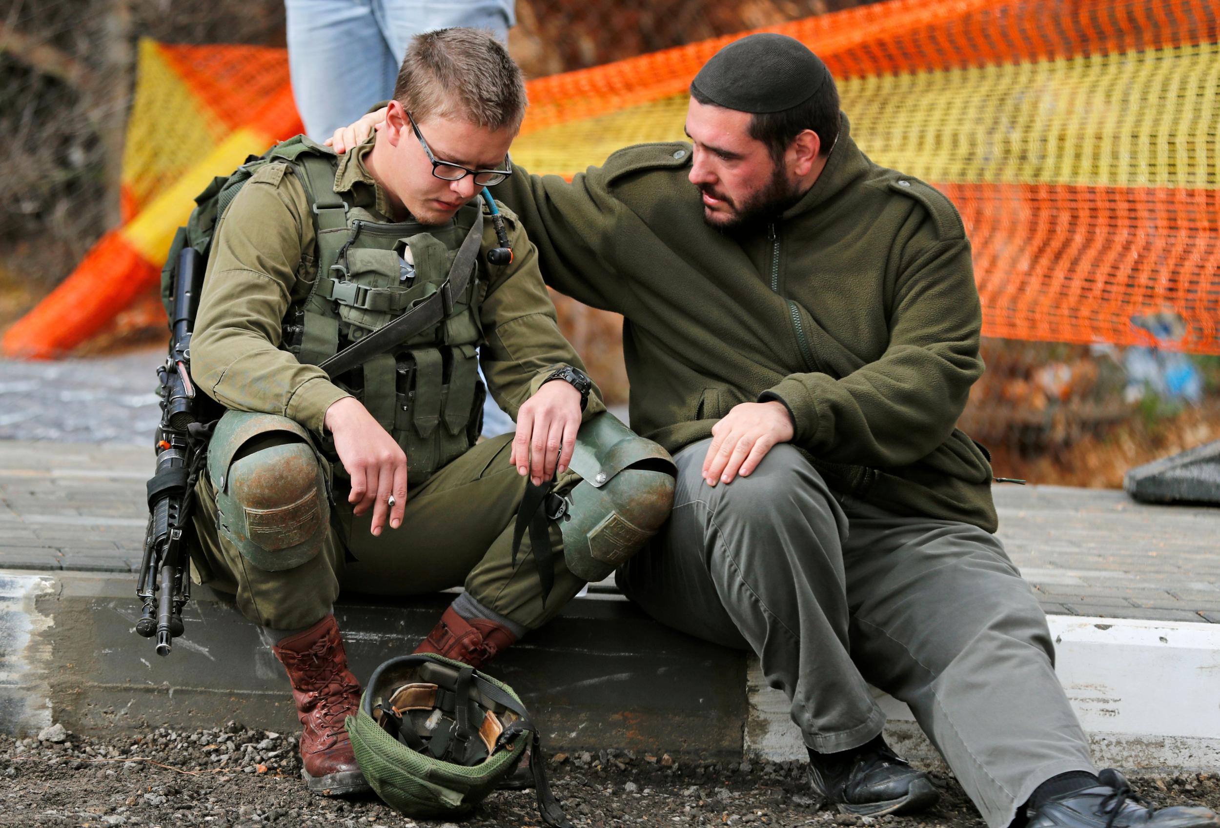An Isreali soldier is consoled at the site of a Palestinian drive-by shooting attack outside the West Bank settlement of Givat Asaf, northeast of Ramallah ( AHMAD GHARABLI/AFP/Getty Images))
