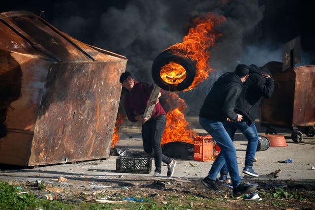 A Palestinian uses a piece of wood to move a burning tire during clashes with Israeli troops in Ramallah, near the settlement of Beit El, in the occupied West Bank