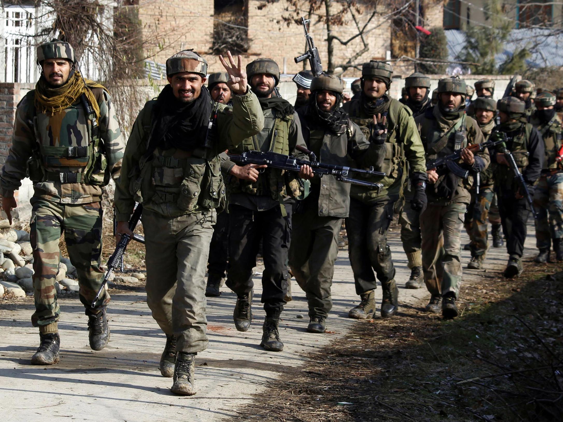 Soldiers walk near the site of a gun battle in Kashmir