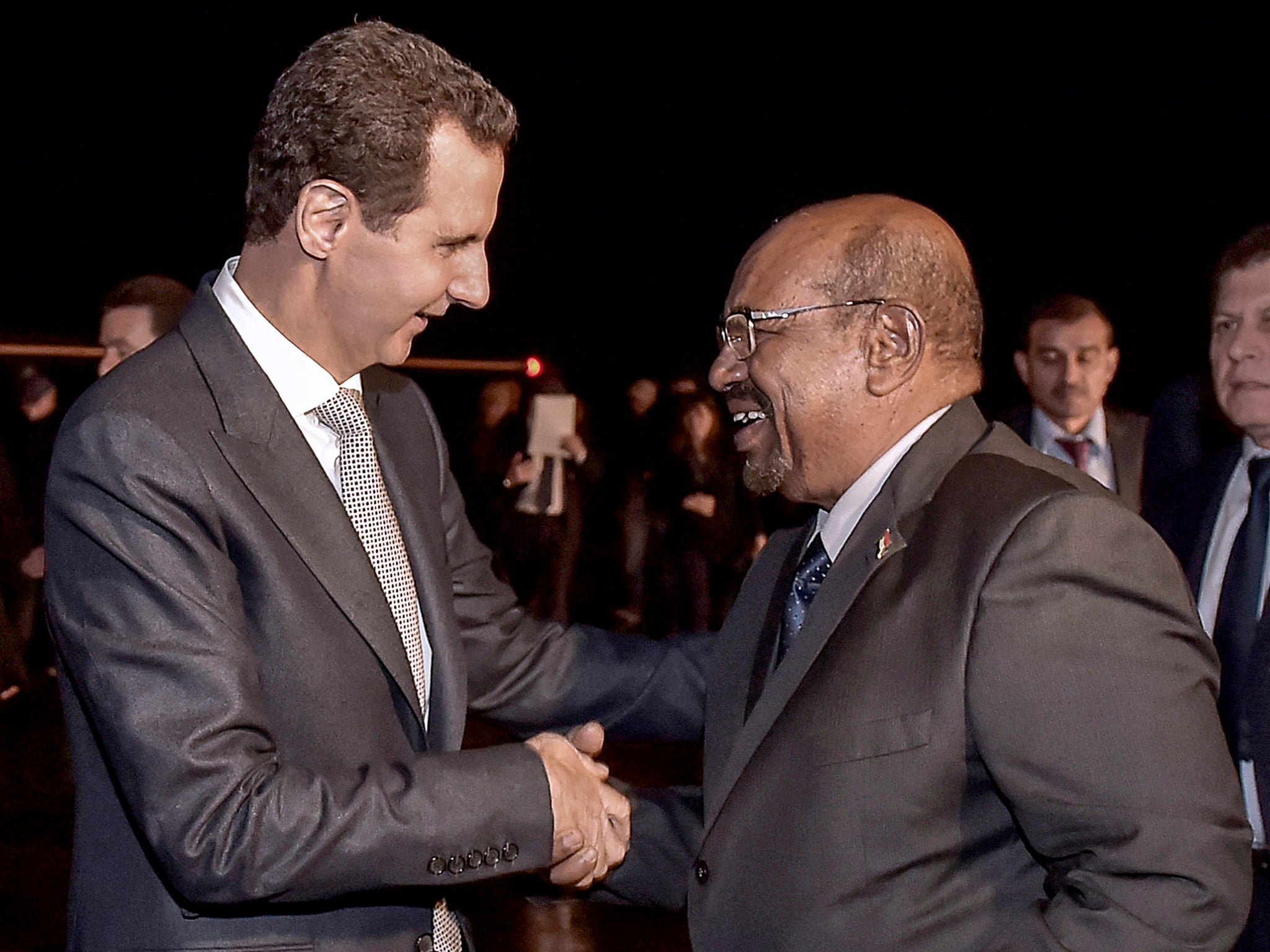 Criminal minds: Syrian president Bashar al-Assad, left, welcomes Omar al-Bashir at Damascus airport on Sunday