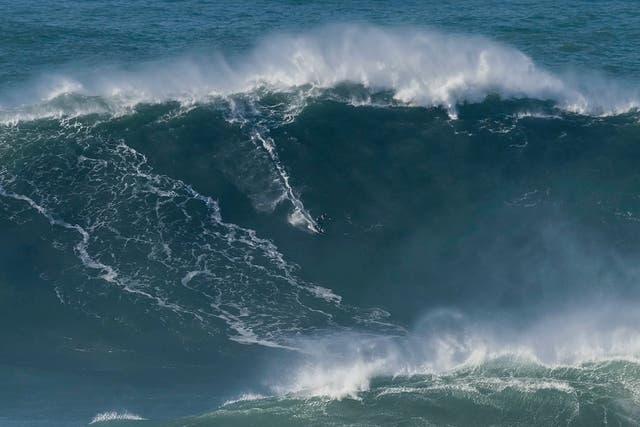 Tom Butler riding the wave estimated to be a more than 100ft tall at Nazare in Portugal