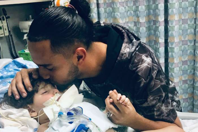 Ali Hassan kisses his two-year-old son, Abdullah, who is dying from a genetic brain condition. Mr Hassan's Yemeni wife has just been granted a visa to say goodbye to her son.