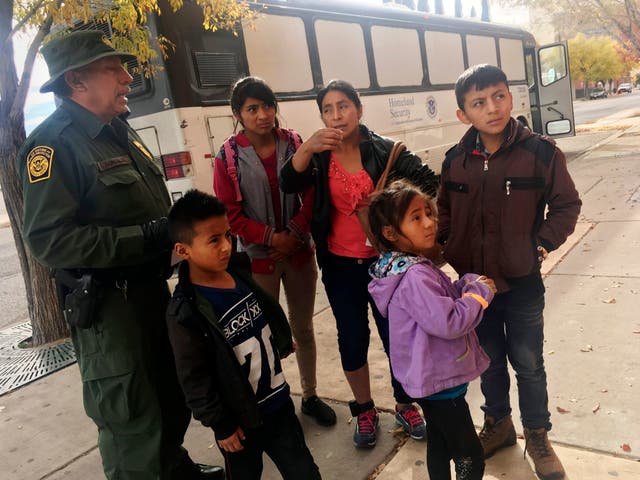 In this Thursday, 29 November 2018 photo, a migrant family from Central America waits outside the Annunciation House shelter in El Paso, Texas