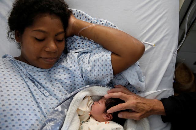 Honduran migrant Alvin Reyes touches his newborn son Alvin, next to his wife Erly Marcial at a hospital in Puebla, Mexico