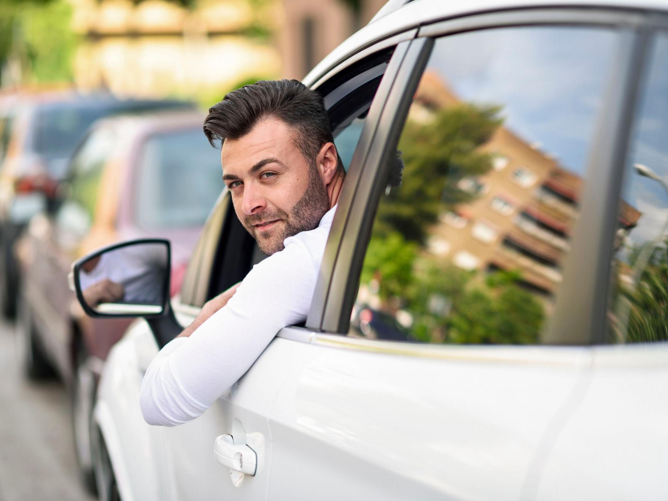 Man leaning out the window of his car in the city