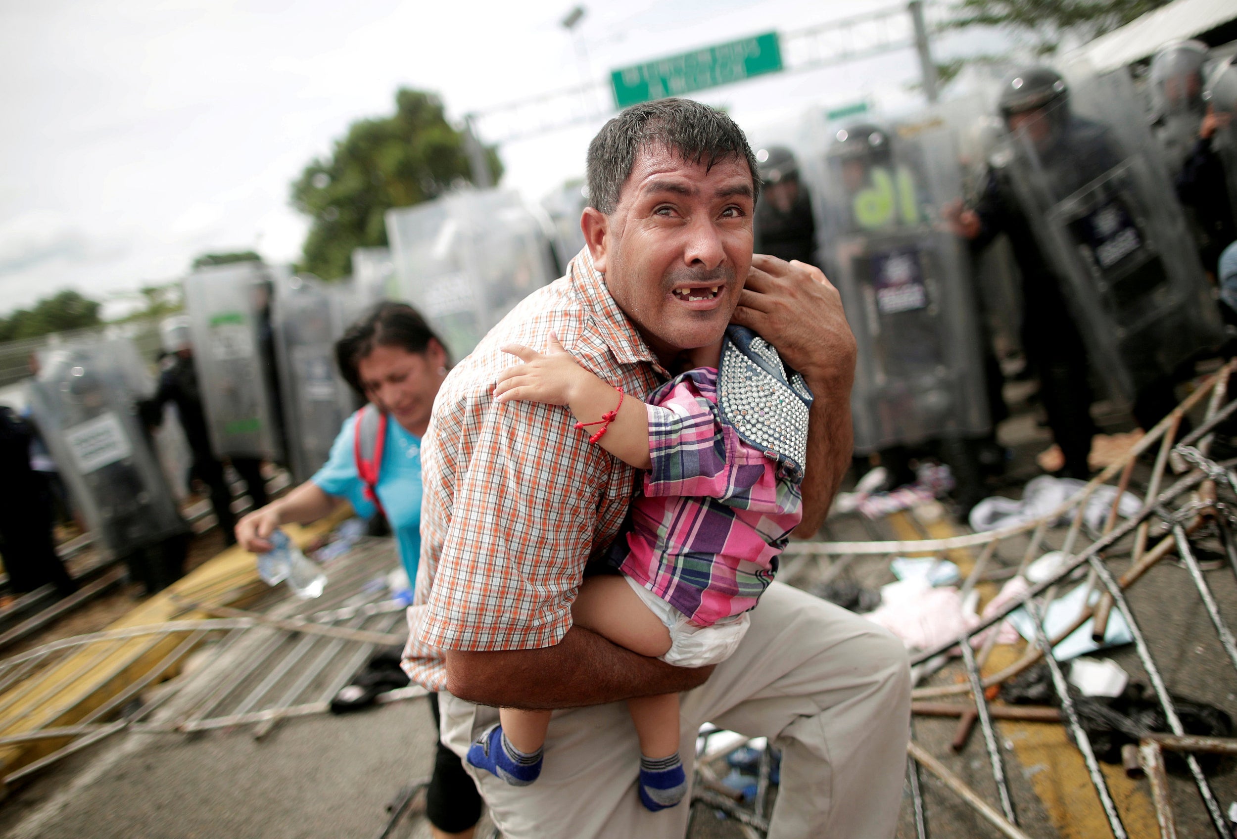 A Honduran migrant protects his child, as part of a caravan trying to reach the US stormed a border checkpoint in Guatemala near Mexico in October