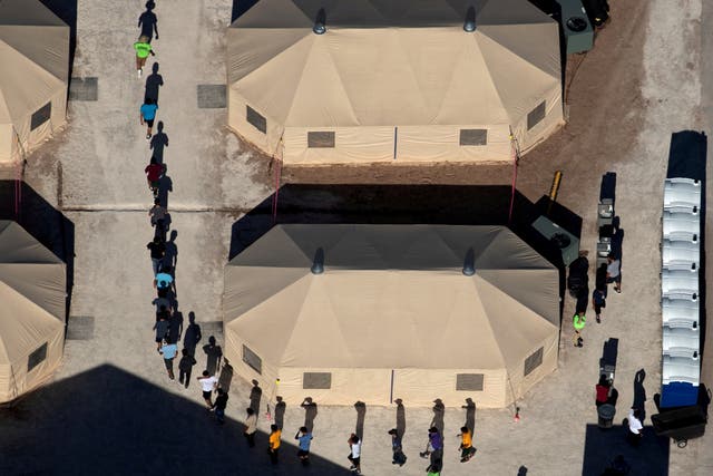 Migrant children are led by staff in single file between tents at a detention facility next to the Mexican border in Tornillo, Texas