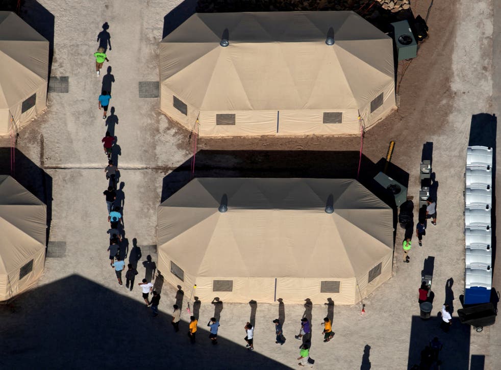 Migrant children are led by staff in single file between tents at a detention facility next to the Mexican border in Tornillo, Texas