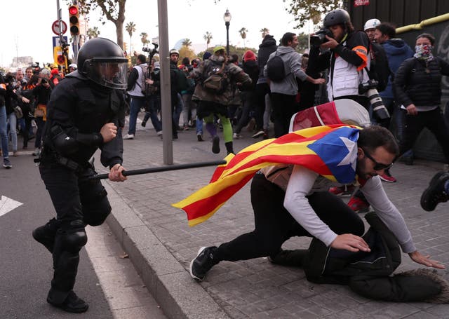 A police officer runs after a demonstrator during a protest against Spain's cabinet meeting in Barcelona