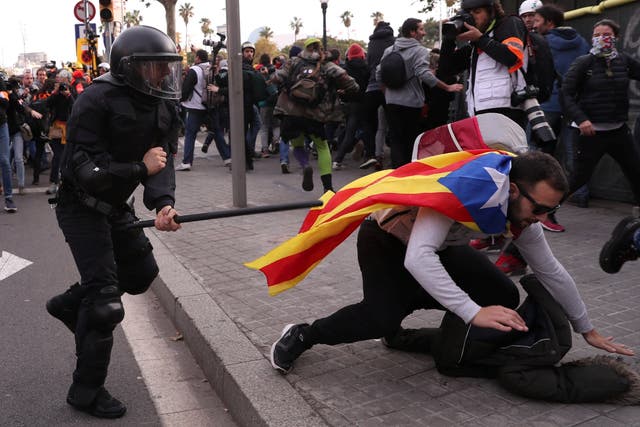 A police officer runs after a demonstrator during a protest against Spain's cabinet meeting in Barcelona