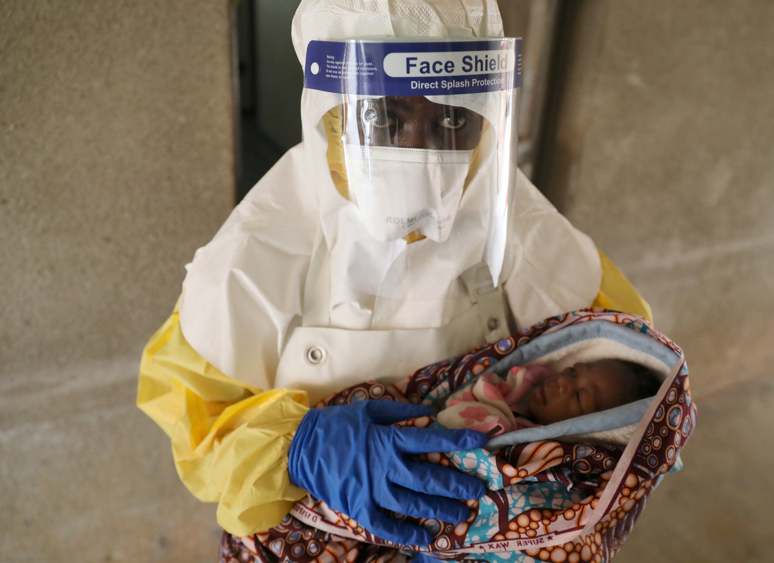 A healthcare worker carries a baby suspected of being infected with Ebola virus in a hospital in Oicha, North Kivu