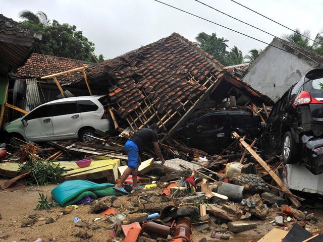 A resident searches for items among the ruins of a villa after the area was hit by a tsunami