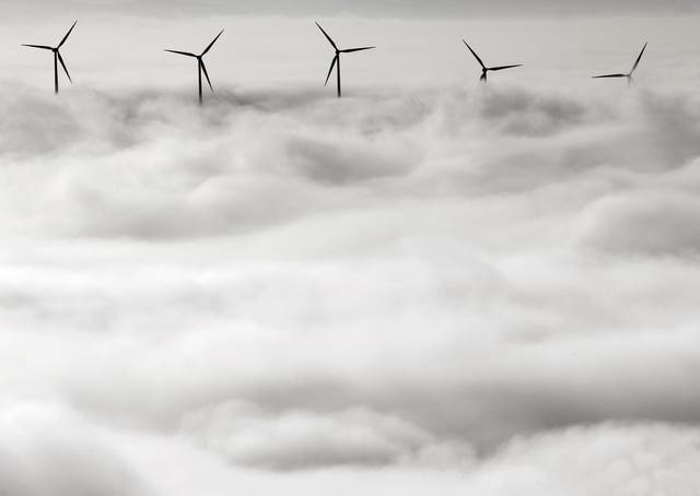 Los aerogeneradores sobresalen del denso manto de niebla que cubre Pamplona, al norte de España
