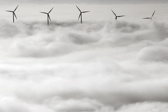 Los aerogeneradores sobresalen del denso manto de niebla que cubre Pamplona, al norte de España