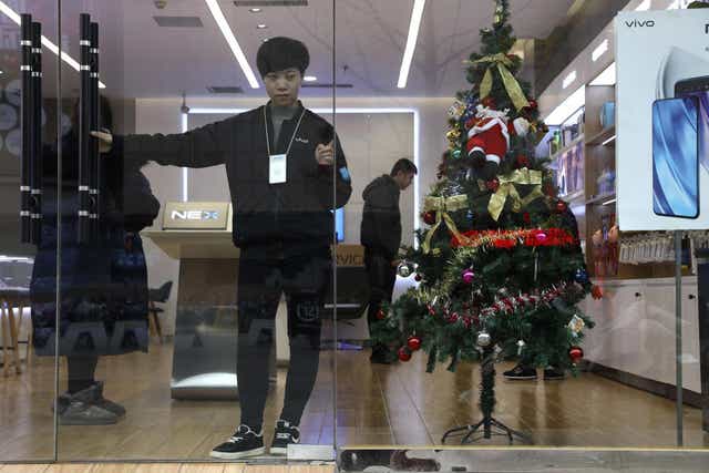 A sales person waits for customers near a Christmas tree decoration in Zhangjiakou in northern China's Hebei province. At least four Chinese cities and one county have ordered restrictions on Christmas celebrations this year.