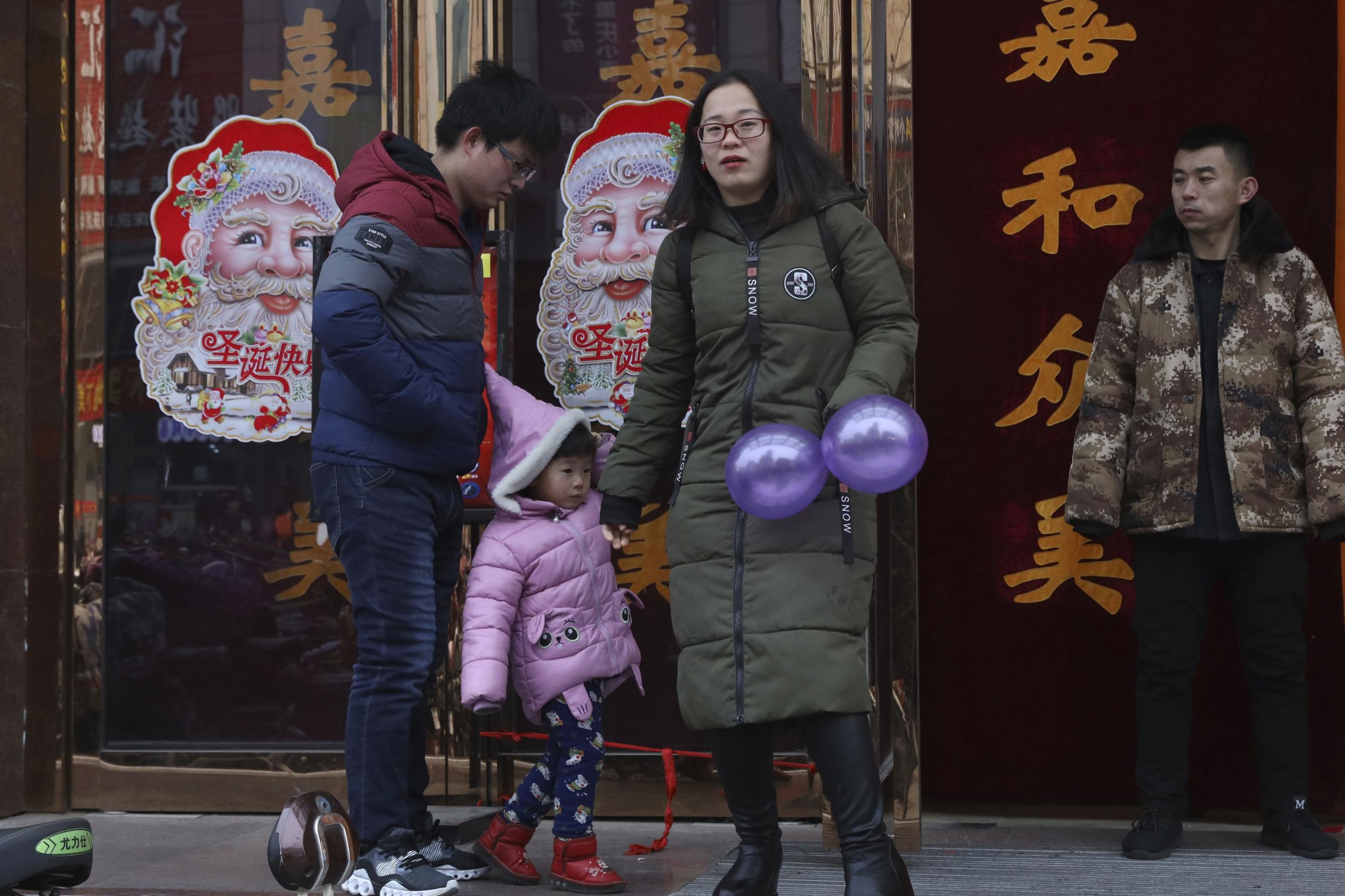 A family walk past images of Santa Claus in Zhangjiakou in northern China's Hebei province.