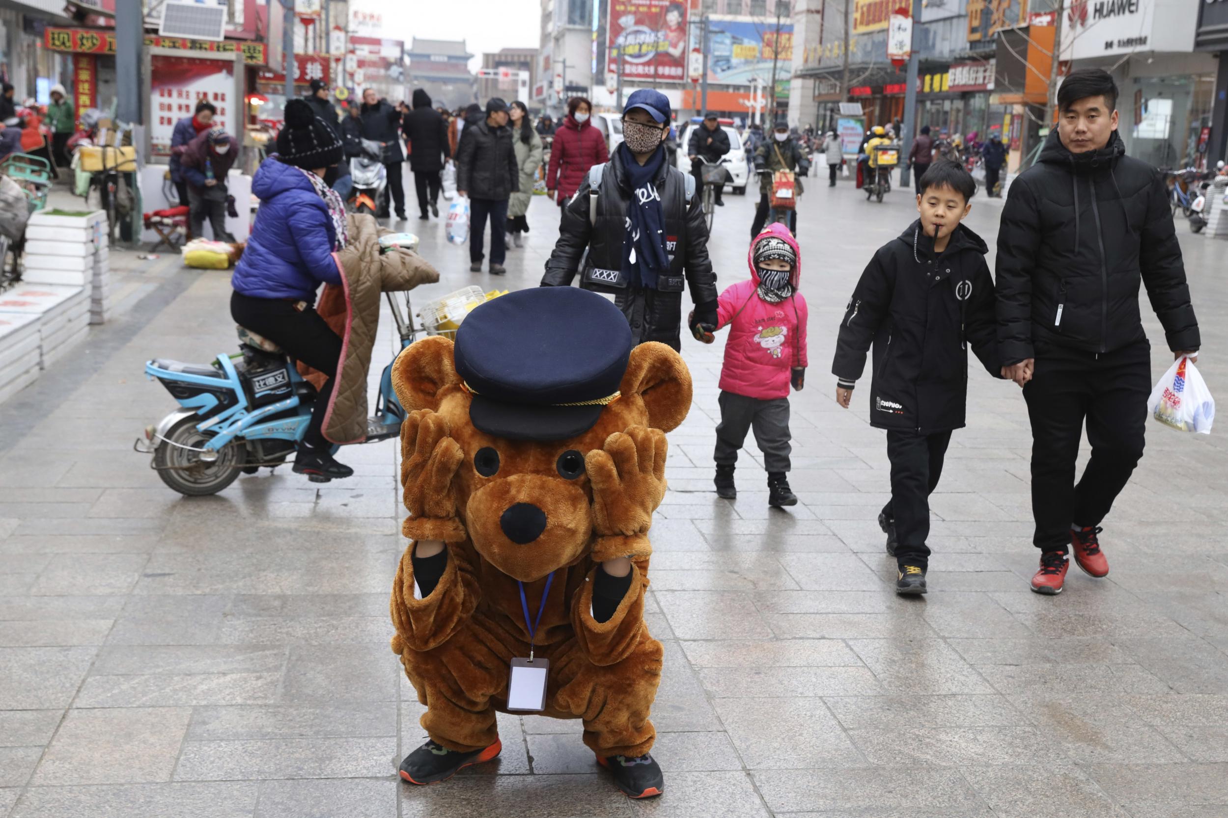 a promoter dressed as a teddy bear rest along a retail street in Zhangjiakou in northern China's Hebei province