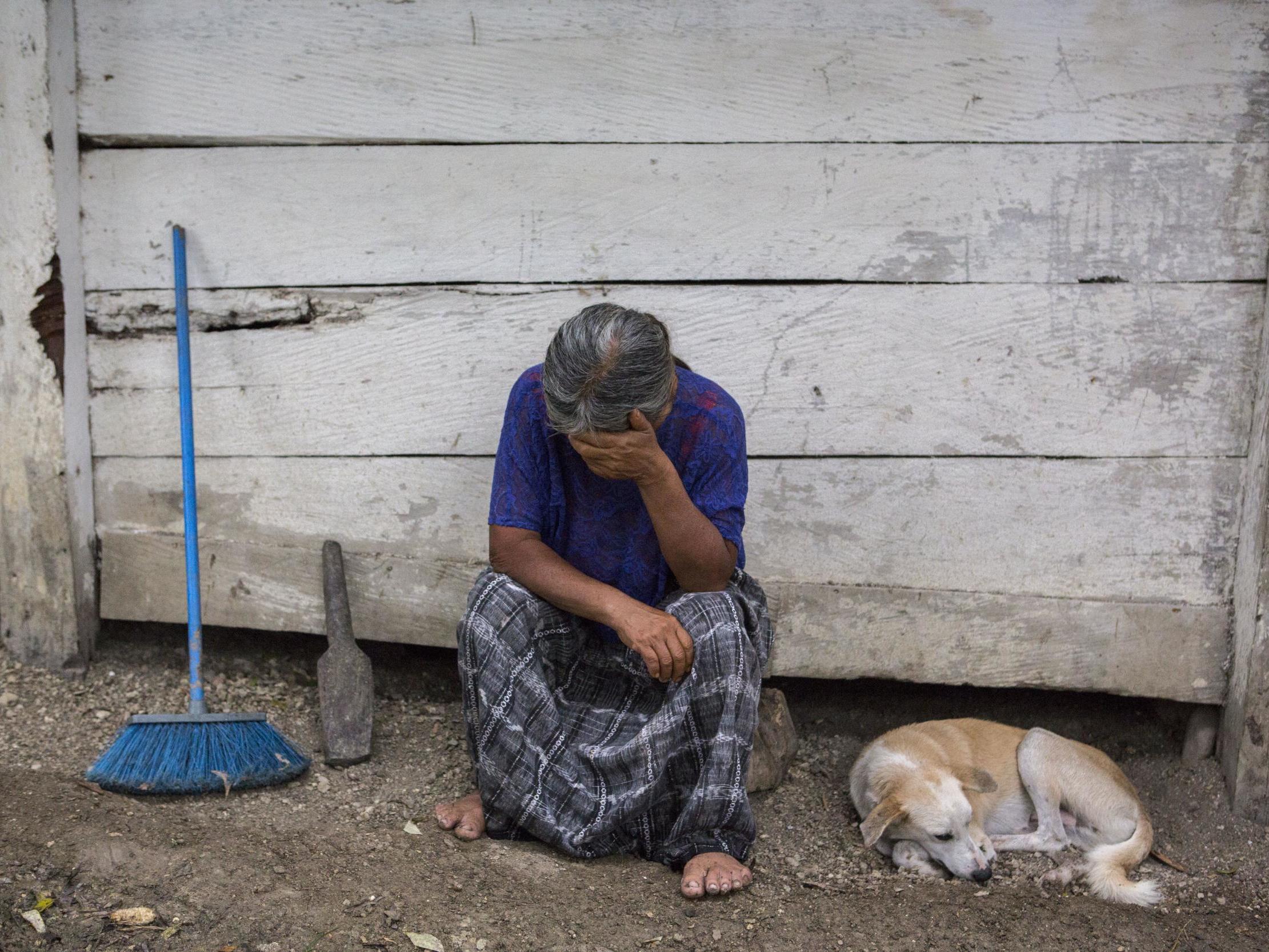 Elvira Choc, 59, Jakelin Amei Rosmery Caal's grandmother, rests her head on her hand in front of her house in Raxruha, Guatemala, on Saturday 15 December 2018. ( (AP Photo/Oliver de Ros))