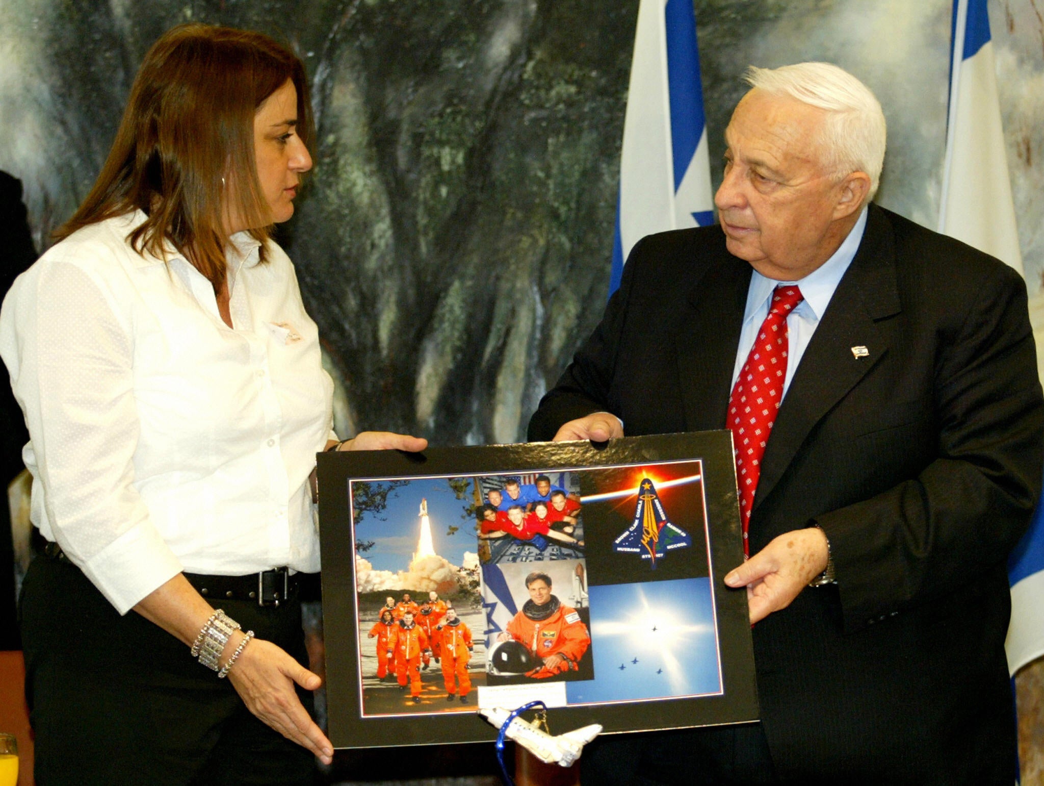 Ramon presents photographs of her husband and and Columbia crew members to Israeli prime minister Ariel Sharon in Jerusalem in 2004