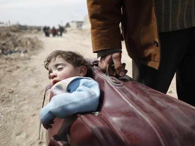 In Beit Sawa, eastern Ghouta, a man carrys a child in a suitcase towards Hamourieh, where an evacuation point has been opened