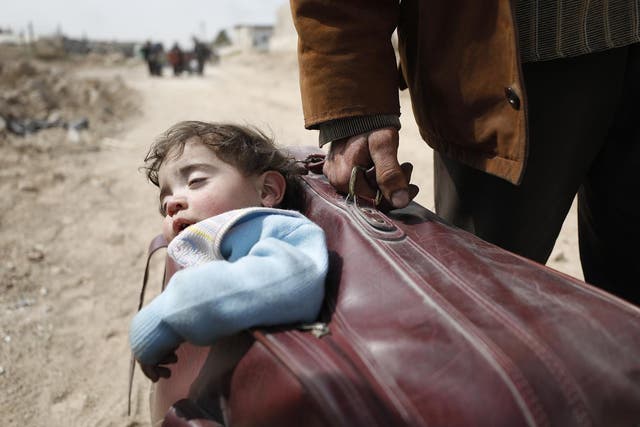 In Beit Sawa, eastern Ghouta, a man carrys a child in a suitcase towards Hamourieh, where an evacuation point has been opened