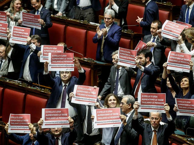 MPs from the centre-left Democratic Party hold up signs in protest against Italy's new budget