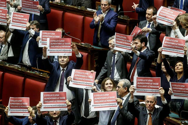 MPs from the centre-left Democratic Party hold up signs in protest against Italy's new budget
