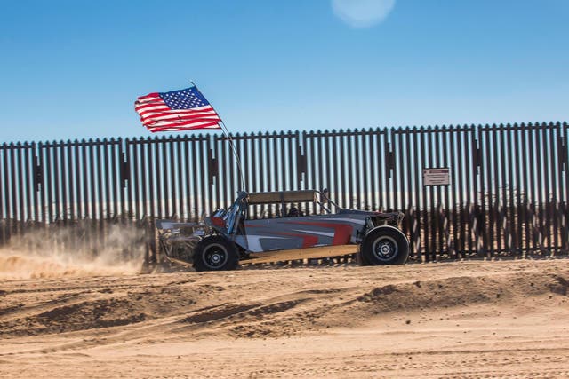 An off-road vehicle with a US flag drives near the US-Mexico border fence at the Imperial Sand Dunes Recreation Area east of Calexico, California, on December 30, 2018.