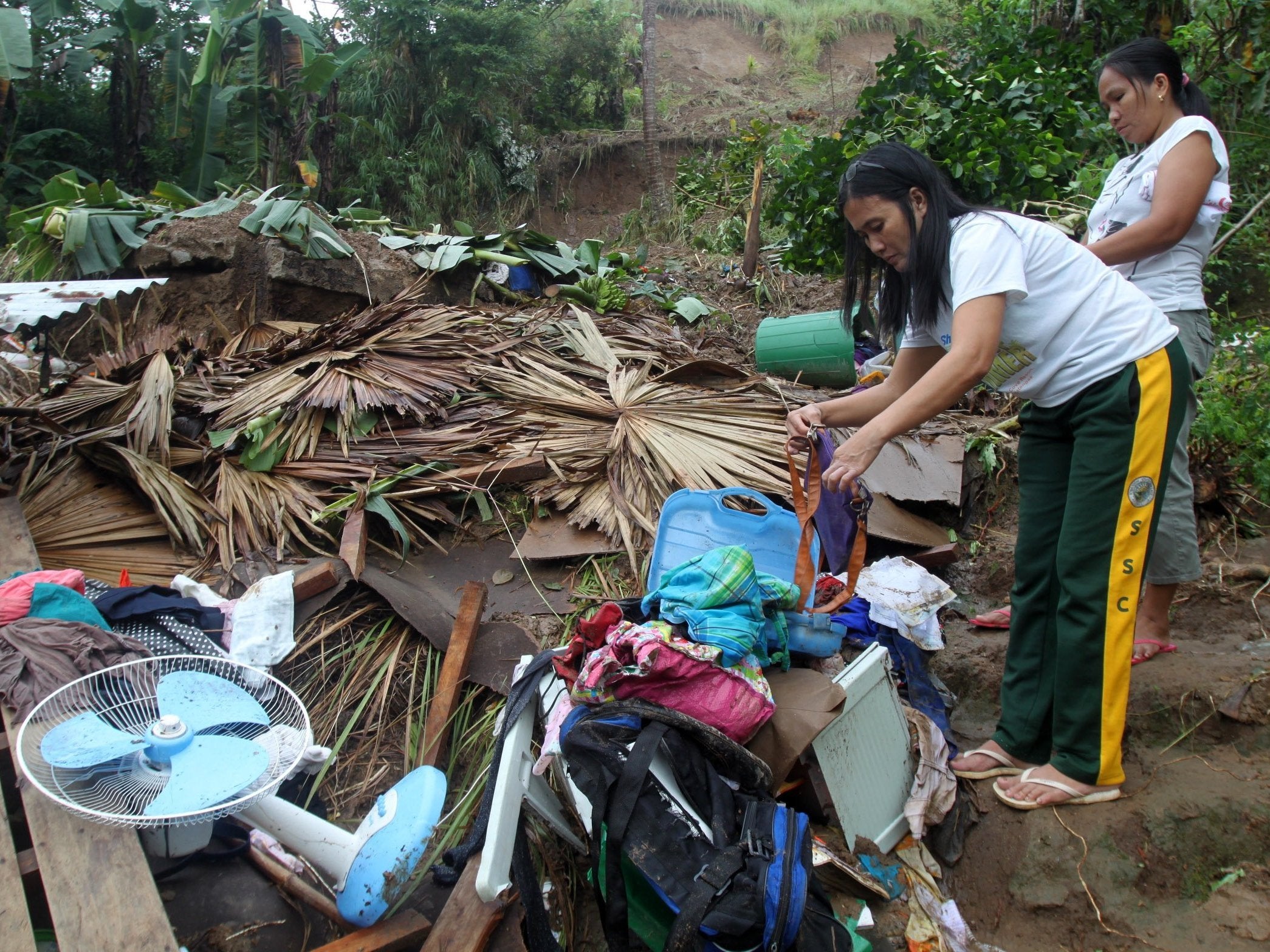 Filipino residents collect belongings from their damaged home at the landslide-hit community in Bulan, Sorsogon province