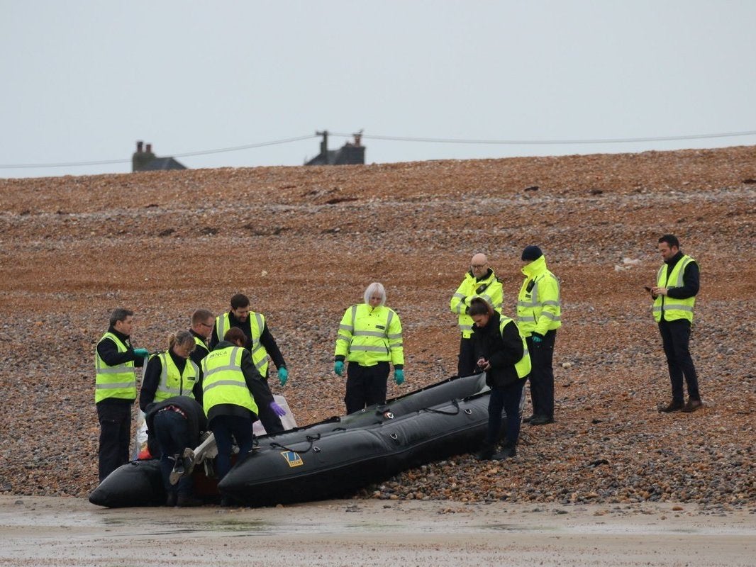 Border Force officials carry an intercepted migrant dinghy off the Kent coast