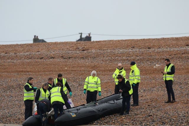Border Force officials carry an intercepted migrant dinghy off the Kent coast