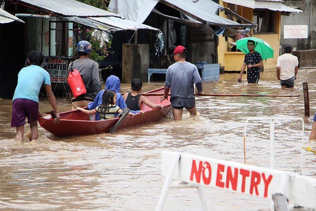 People wade through a flooded street in the town of Baao in Camarines Sur province on December 30, 2018