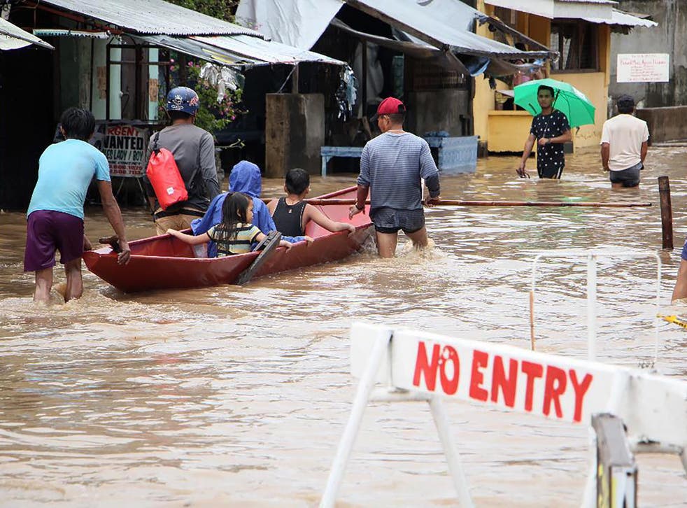 People wade through a flooded street in the town of Baao in Camarines Sur province on December 30, 2018