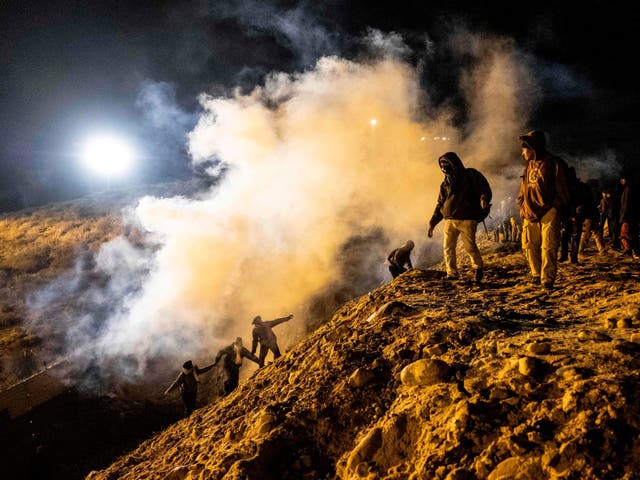 Central American migrants run away from tear gas thrown by the US border patrol