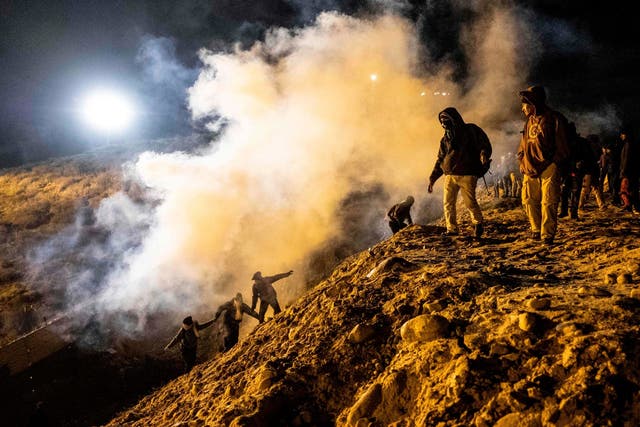 Central American migrants run away from tear gas thrown by the US border patrol