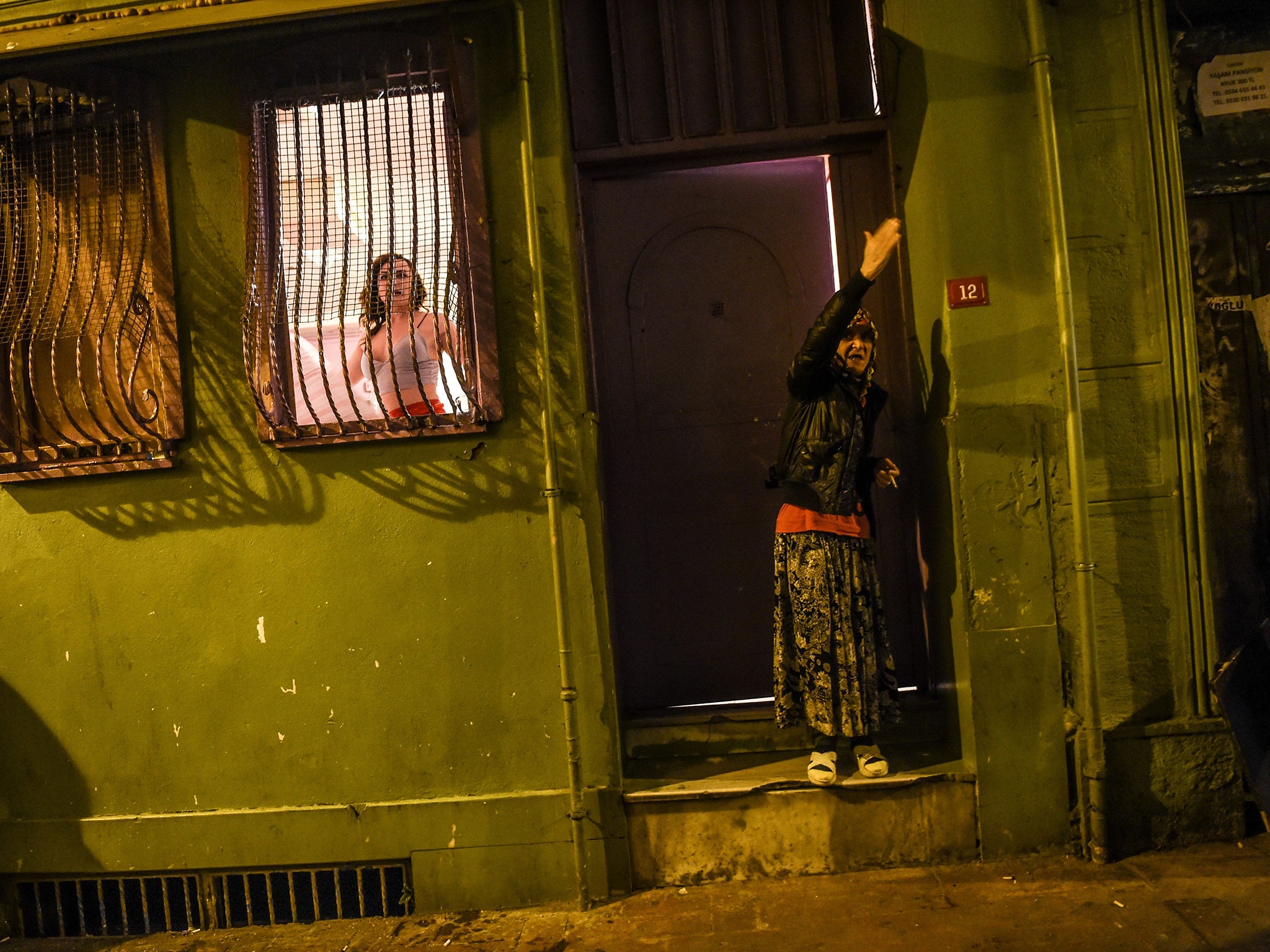 A transgender woman looks out of a window and a woman reacts as women’s rights activists march through Taksim Square to protest against gender violence