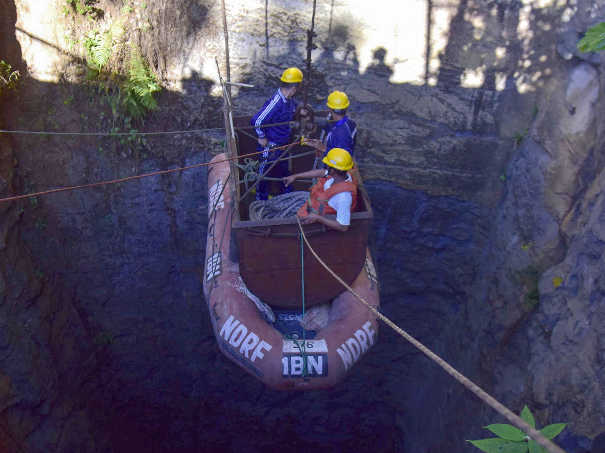 Indian Navy divers are lowered into the illegal coal pit in Meghalaya where 15 miners have been trapped for over three weeks as part of the rescue operation
