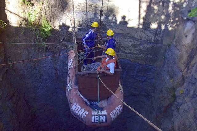 Indian Navy divers are lowered into the illegal coal pit in Meghalaya where 15 miners have been trapped for over three weeks as part of the rescue operation