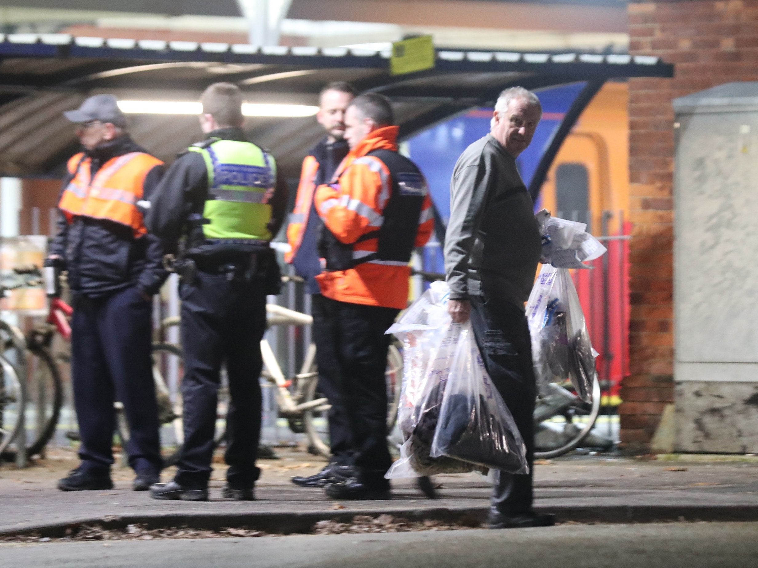 A forensics officer removes items at Horsley station near Guildford, following the stabbing of a man on board a train.