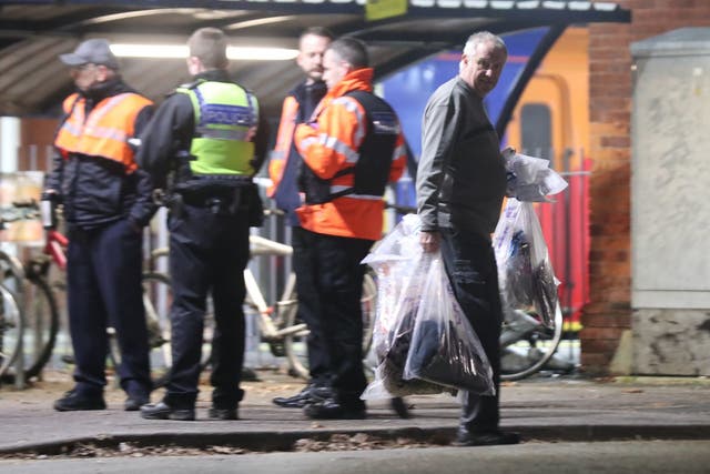 A forensics officer removes items at Horsley station near Guildford, following the stabbing of a man on board a train.